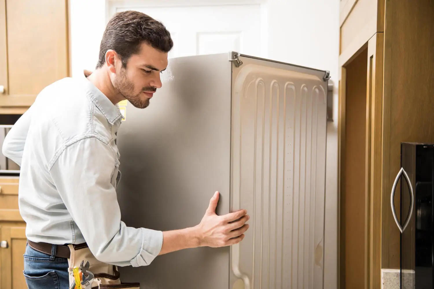 Technician inspecting the back of a refrigerator